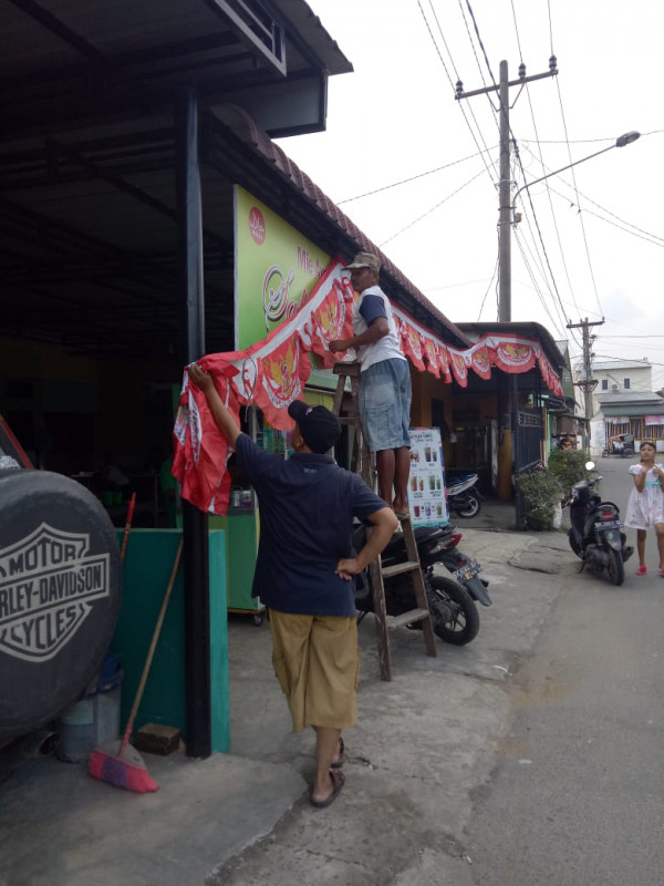 Masyarakat Kampung Kb sedang bergotong royong memasang umbul-umbul bendera 