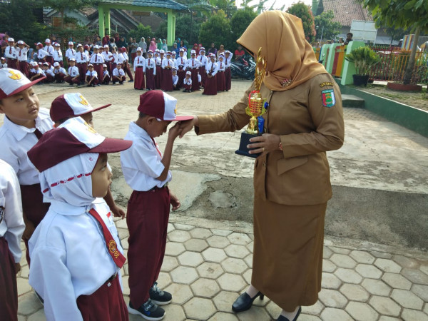 Kepala sekolah sedang membagikan piala kepada siswa yang berprestasi