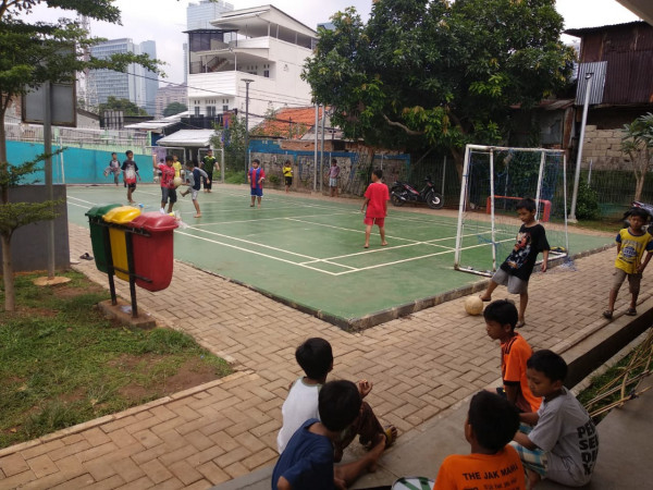 Anak - anak bermain sepak bola di lapangan bulu tangkis