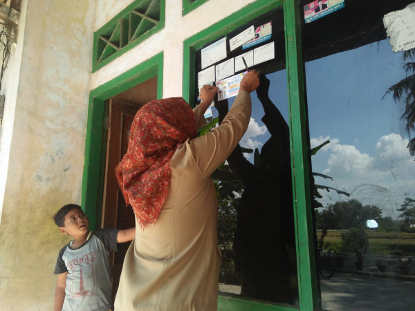 Fasilitator Kampung KB Sedang menempel stiker di fumah salah satu keluarga Baduta