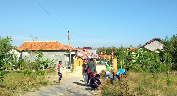 Anak-anak remaja sedang melakukan kerjabakti membersihkan rumput dipinggir jalan