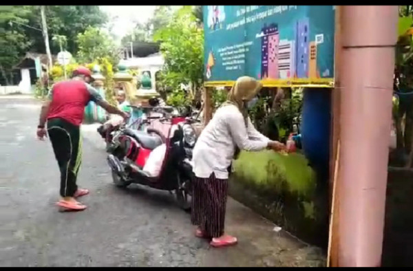 Petugas jaga portal menyemprot motor yang masuk