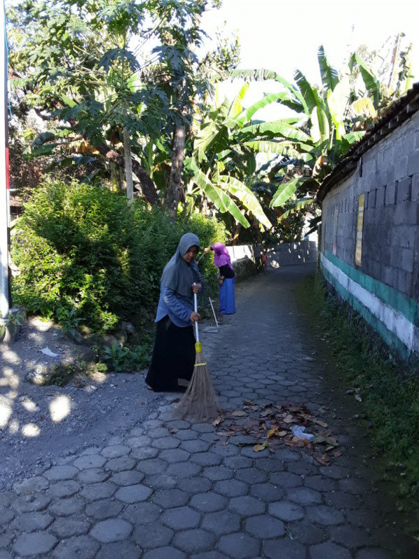 Ibu-ibu sedang membersihkan jalan dekat masjid