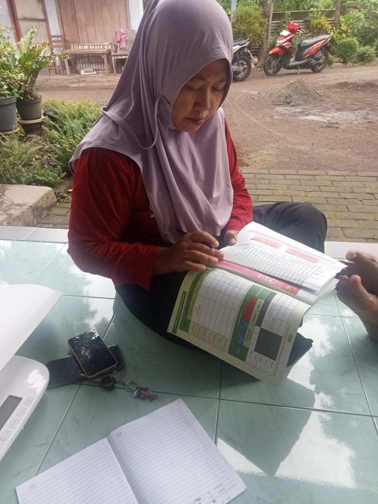 Mencatat hasil penimbangan  di buku KIA balita