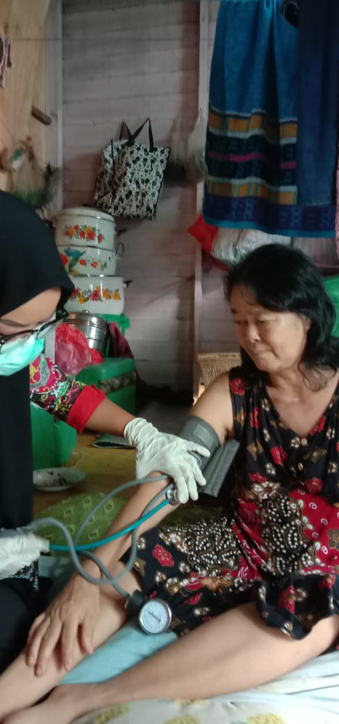 Bidan Kampung Muara Bunyut sedang mengukur tekanan darah lansia