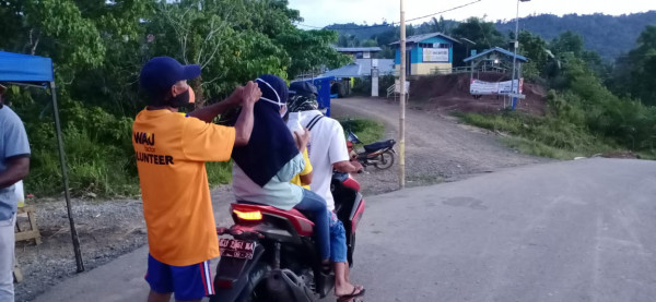 pembagian masker kepada pengguna jalan yang melewati kampung tanpa masker