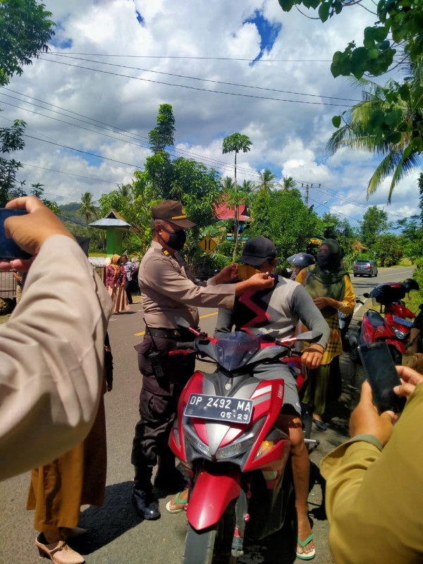 Kapolsekta Bacukiki melakukan pemasangan masker kepada warga yang kedapatan tidak menngunakan masker